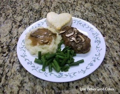 Salisbury Steak with Mushroom Gravy and green beans with heart-shaped biscuit on white plate