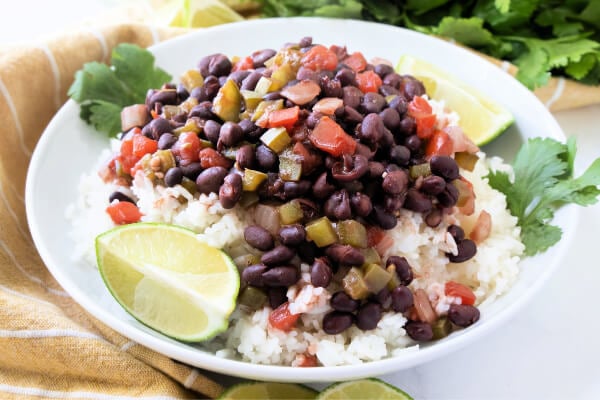 cuban black beans and rice on white plate with lime wedges