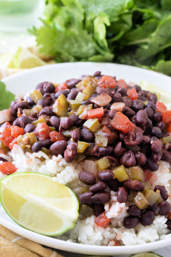 cuban black beans and rice on white plate with lime wedges