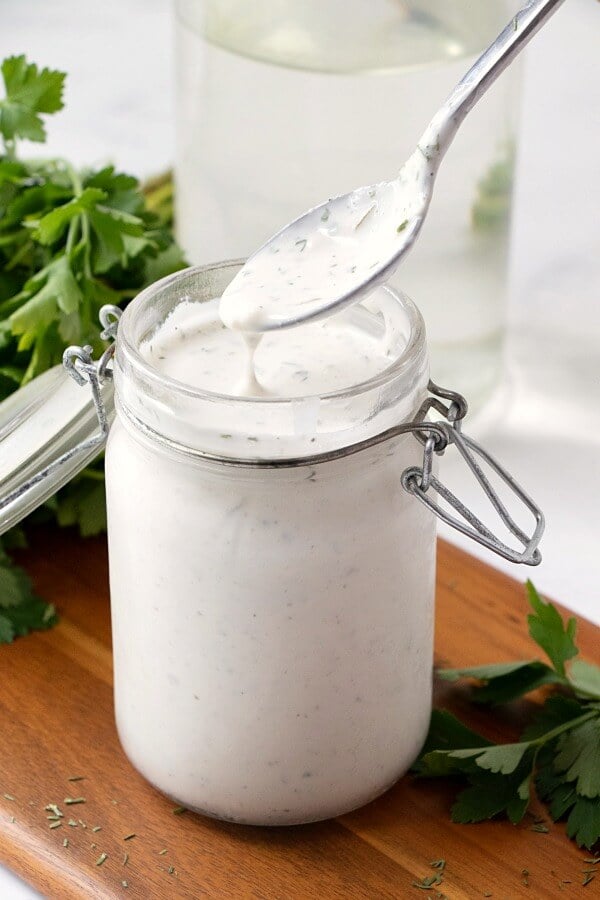 spoon dipped into glass container with homemade ranch dressing
