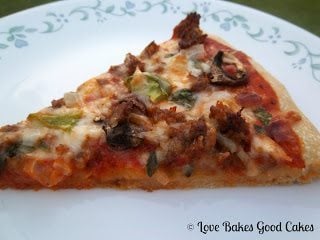 Supreme Pizza slice on plate close up.