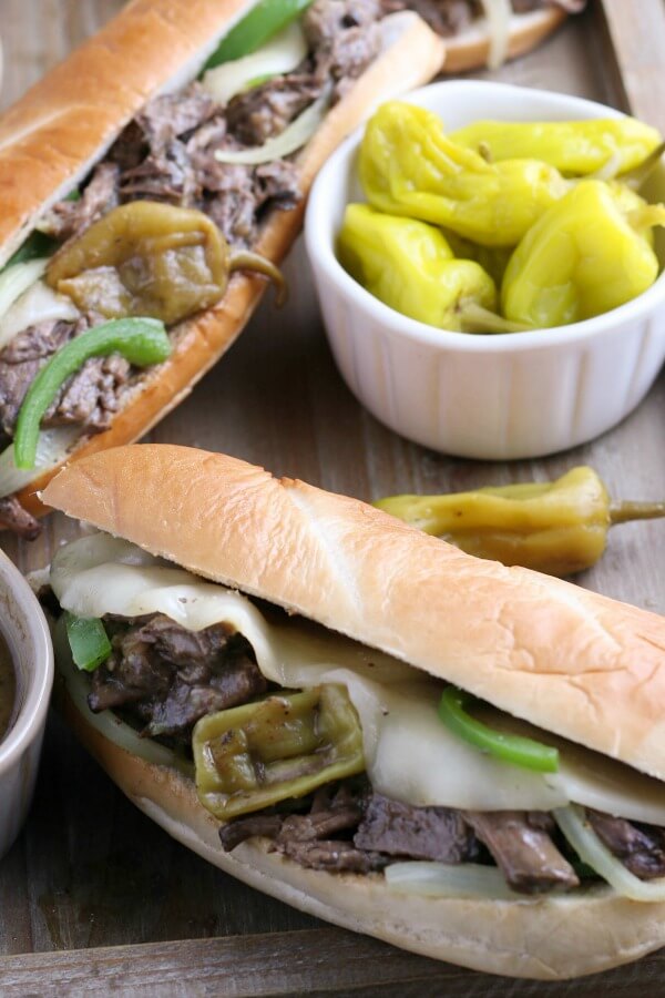 This image shows an Italian beef sandwich with peppers ready to be eaten with melted cheese. 