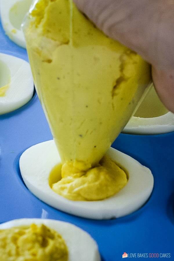 Classic Deviled Eggs yolk mixture being piped into white egg part