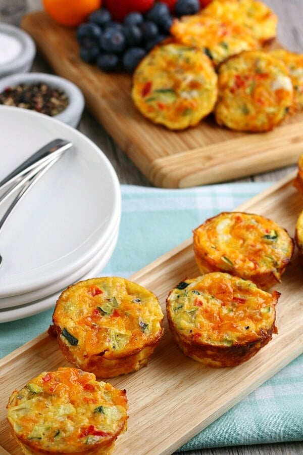 breakfast egg muffins in foreground on cutting board, breakfast table setting in background