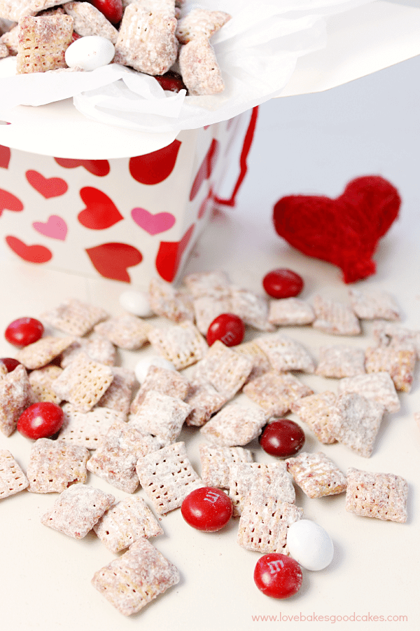Red Velvet Muddy Buddies laying on a table with a carton full.