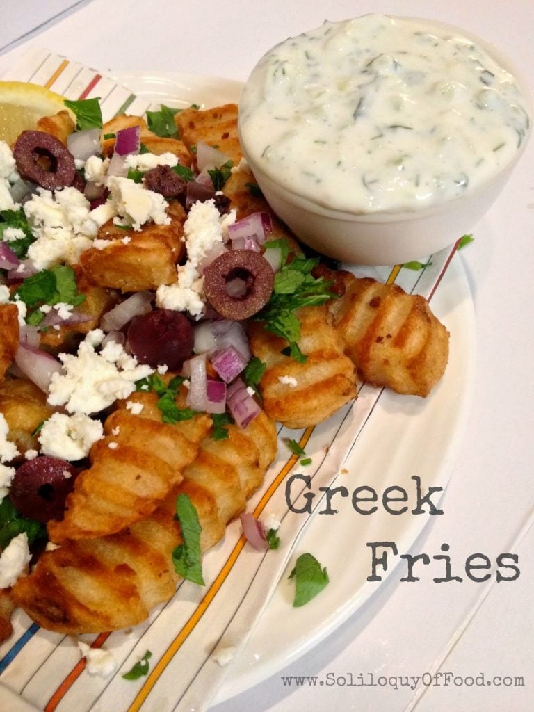 Greek Fries on a plate with a bowl of dip.
