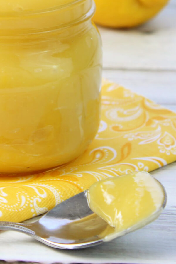 lemon curd on spoon and in glass jar