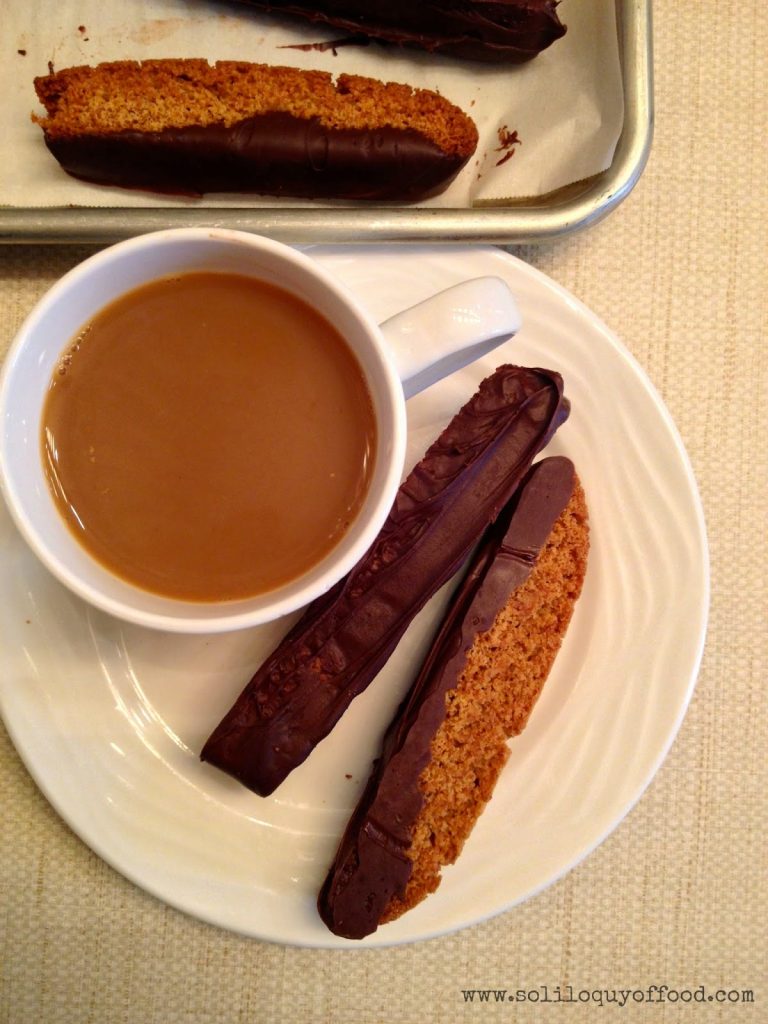 Chocolate Dipped Honey Graham Biscotti on a plate with a cup of caramel. 