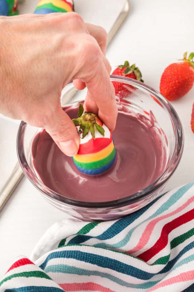 dipping a strawberry into the purple candy melts