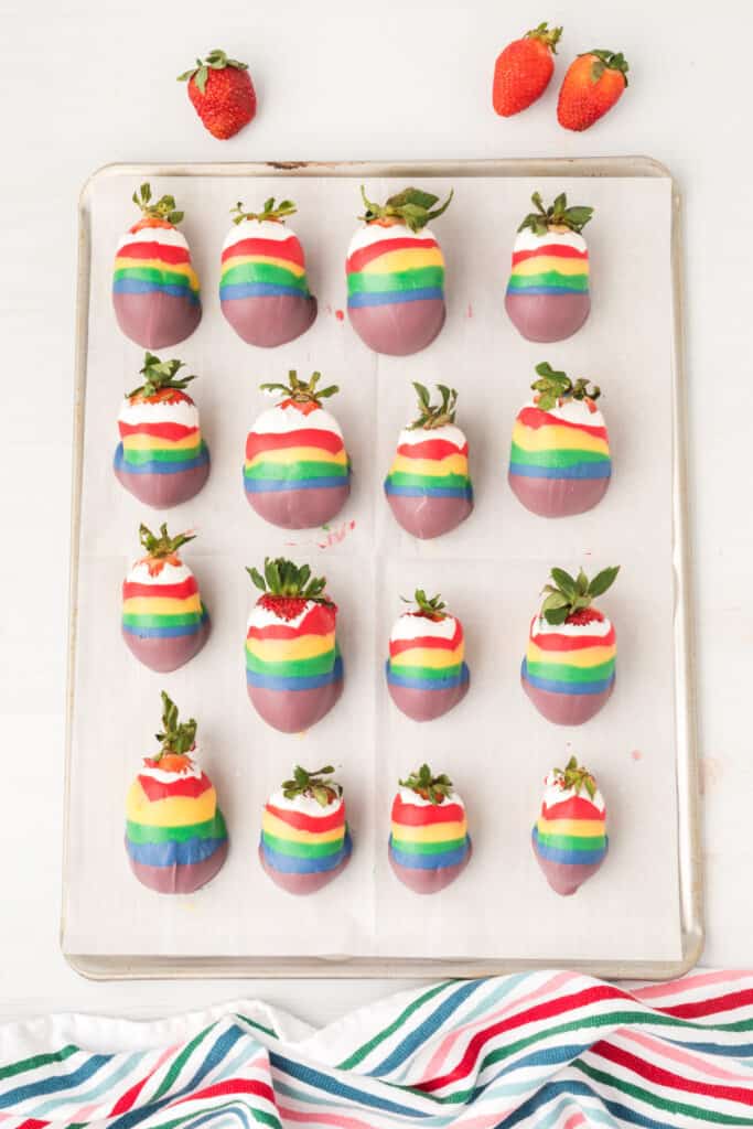 candy coated strawberries on a baking sheet