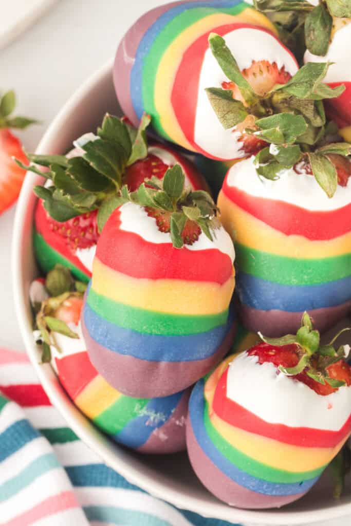 rainbow candy coated strawberries in a white bowl