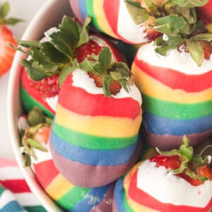 closeup of rainbow candy coated strawberries stacked in bowl