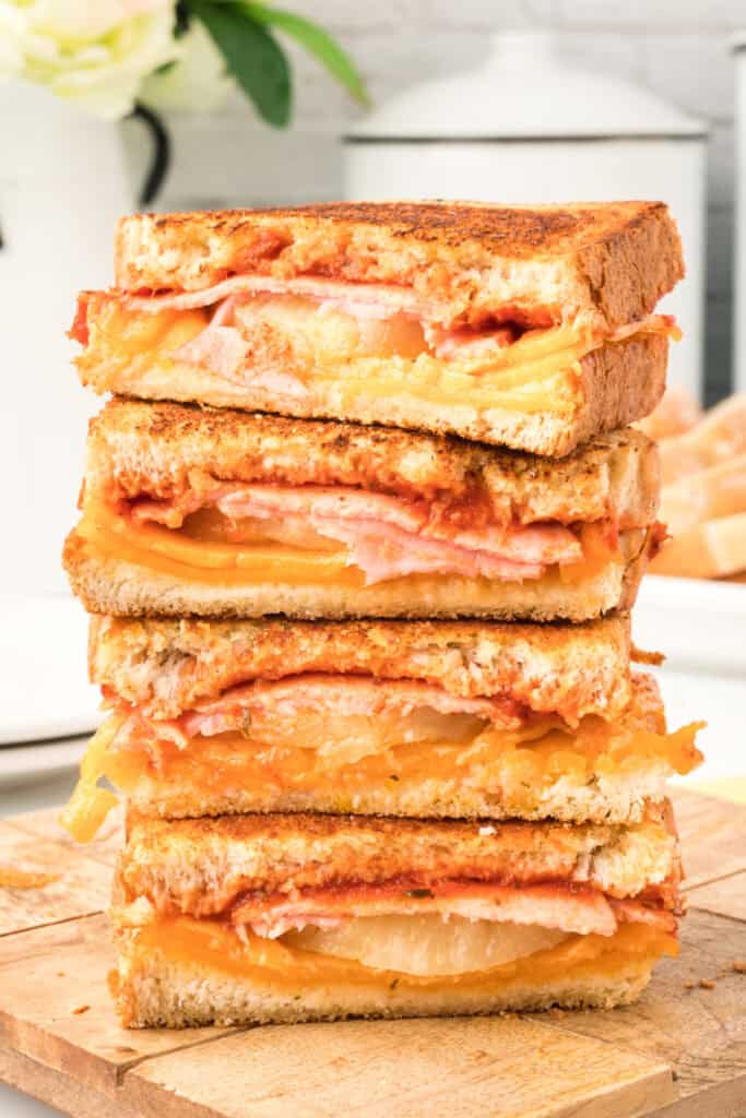 Hawaiian Pizza Grilled Cheese Sandwiches sliced in half and stacked on a cutting board