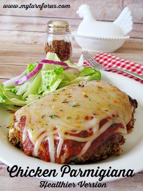 Healthier Version Chicken Parmigiana on a plate with a green salad and a fork.