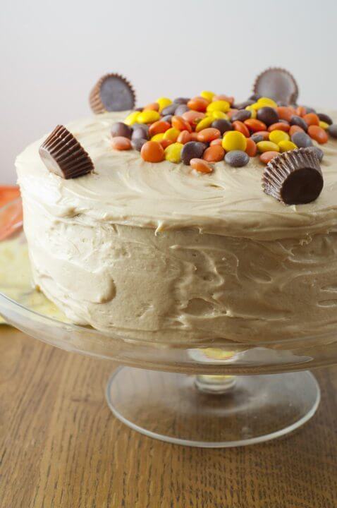 Reese’s Double Peanut Butter Layered Cake on a cake stand with Reese's candies on top.