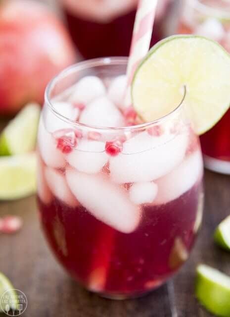  Pomegranate Lime Spritzer in a glass with ice and a slice of lime. valentine's day food ideas