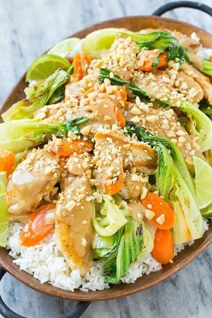 Thai Peanut Chicken in a brown dish with white rice and vegetables. 
