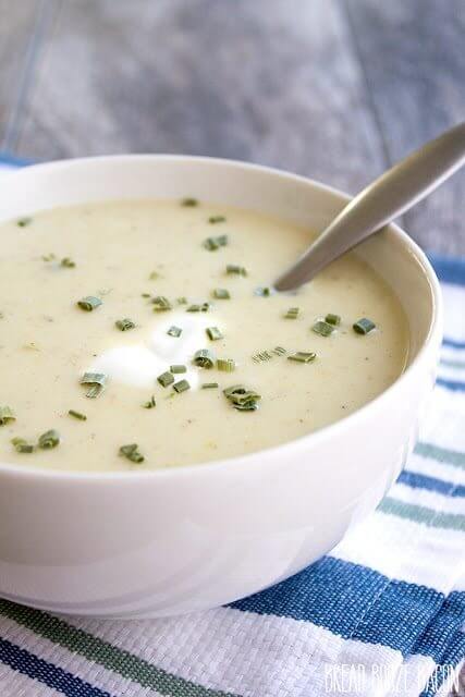 Potato Leek Soup in a white bowl with a spoon. St. Patrick's Day Menu Plan