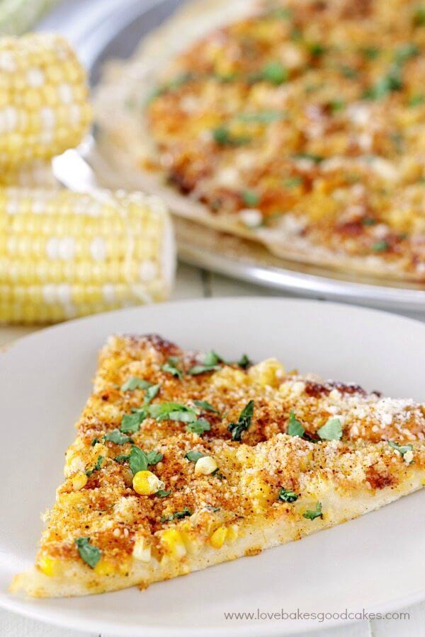 Elote Pizza on a white plate with fresh corn.
