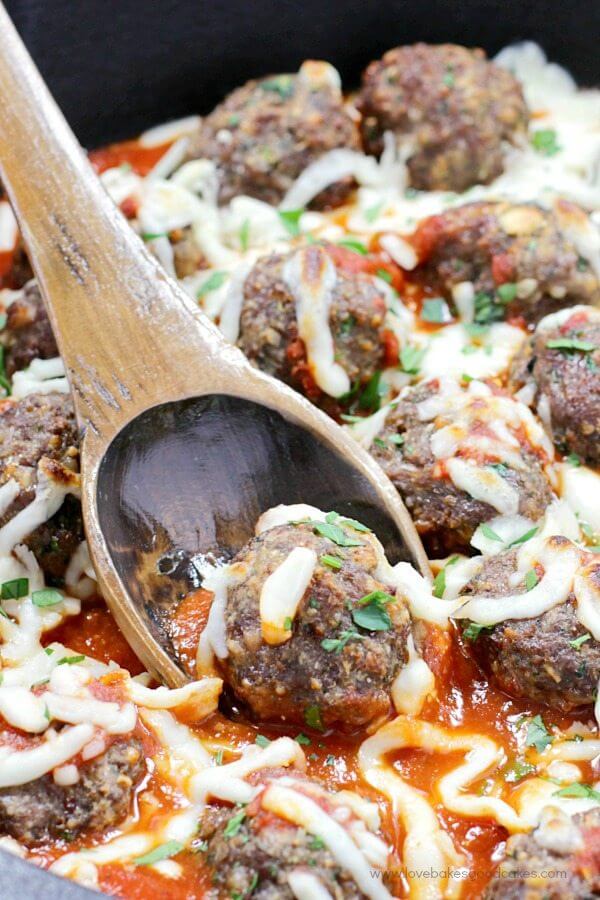 Italian Herb Baked Meatballs in a skillet with a spoon.