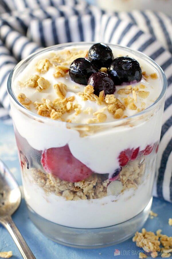 Fruit and Yogurt Breakfast Parfait in a glass with a spoon and fresh fruit.