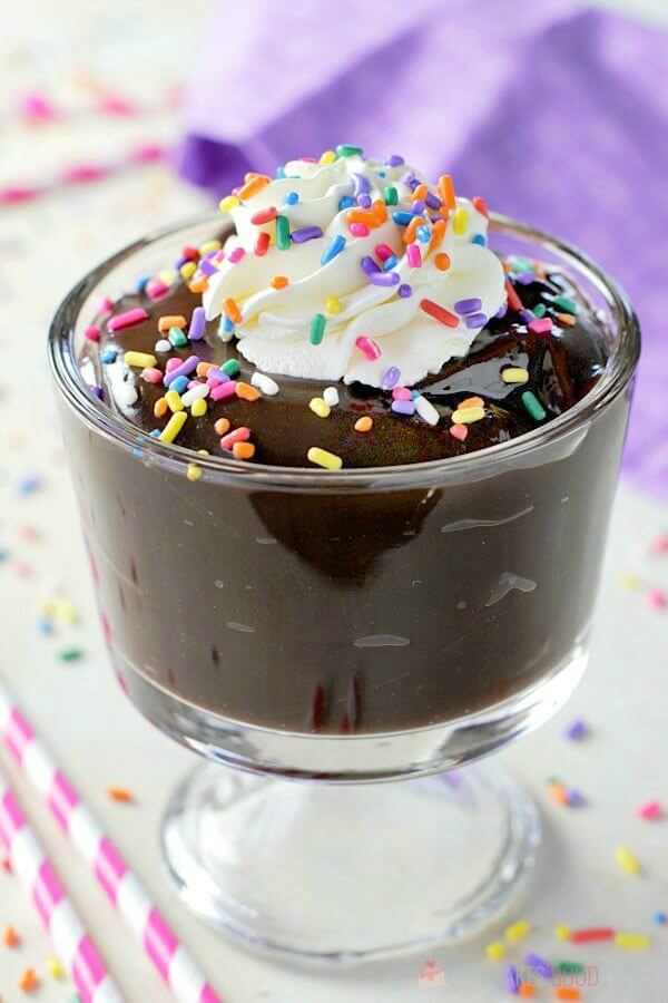 Homemade Chocolate Pudding in a glass cup with whipped cream and rainbow sprinkles.