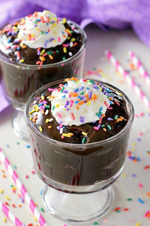 Homemade Chocolate Pudding in two glass cups with whipped cream and rainbow sprinkles close up.