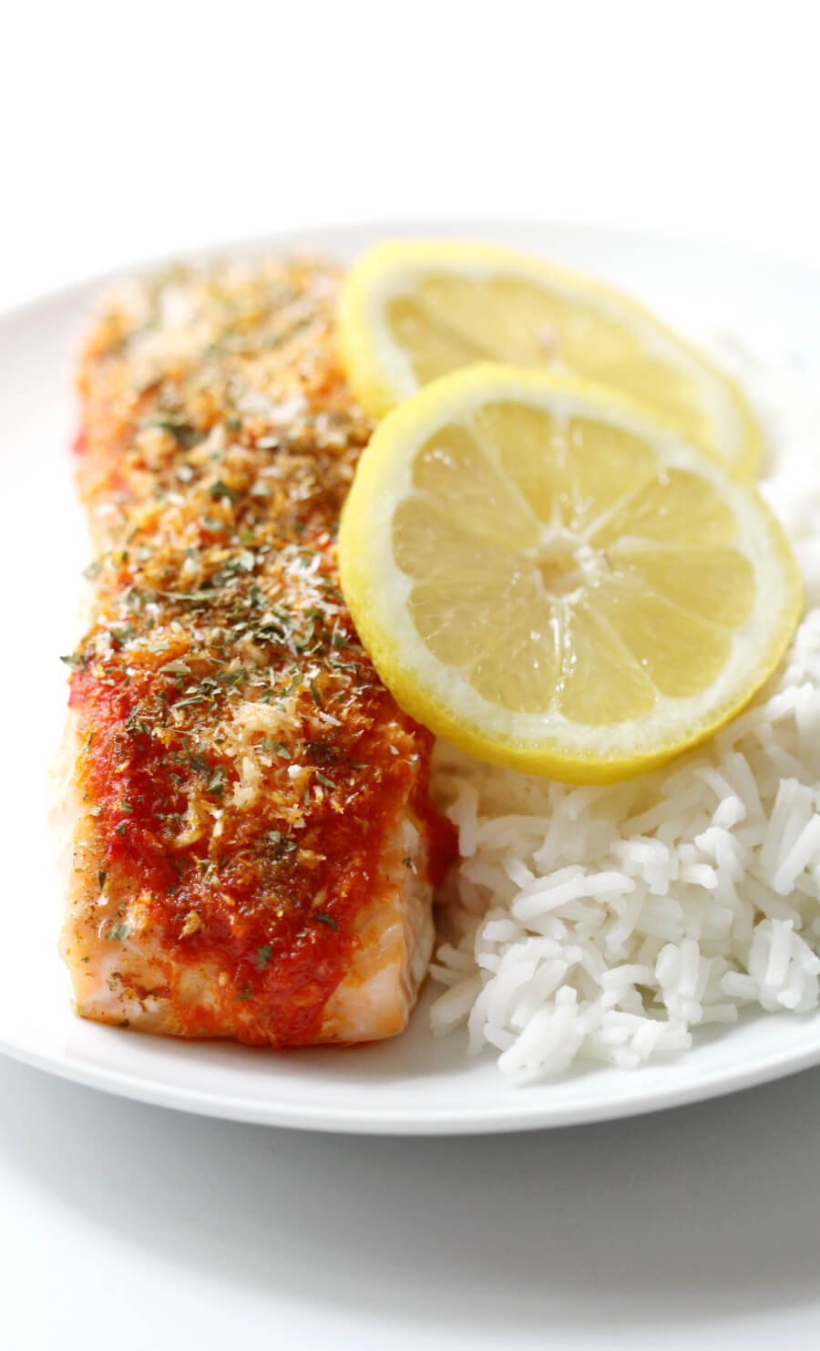 Harissa Salmon with Shredded Coconut on a plate with rice and lemon slices.