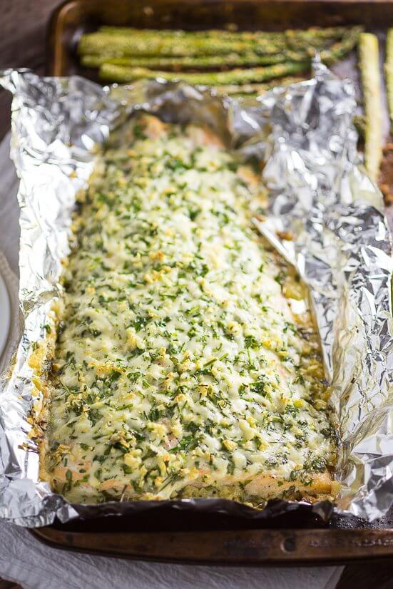 Parmesan Garlic Herb Salmon on a baking pan with asparagus.
