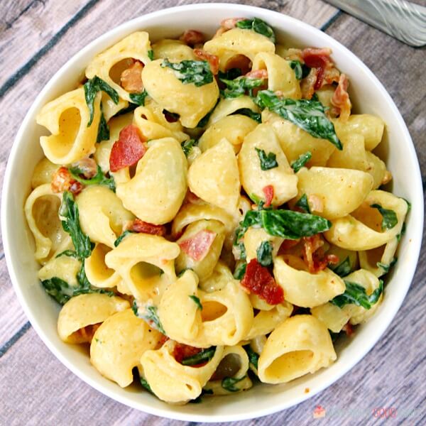 Pasta de espinacas con tocino cremoso en una olla blanca.