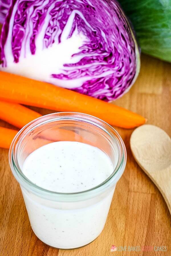 Coleslaw Dressing in a glass cup with fresh vegetables.