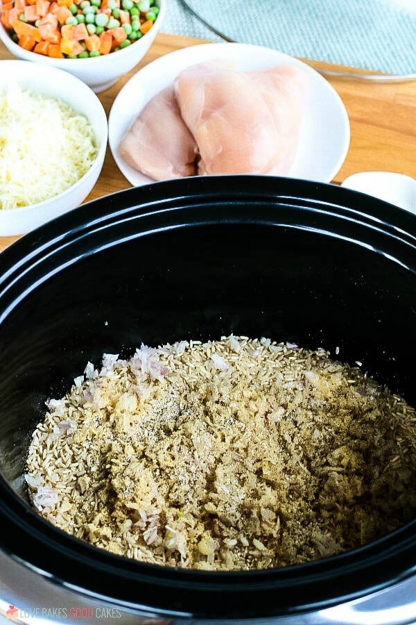 Brown rice and spices added to a slow cooker for chicken and rice.