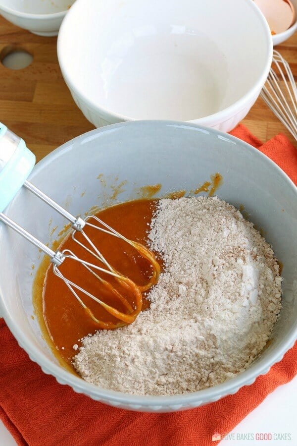 Flour and spices added to a pumpkin mixture to make muffins.