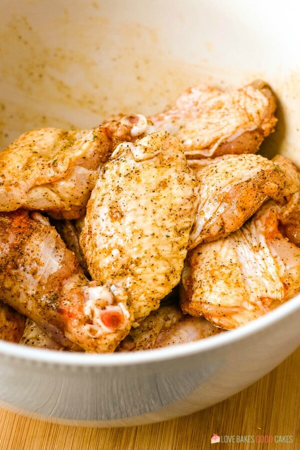 Here we see the frozen wings in a bowl being seasoned before they are cooked. 