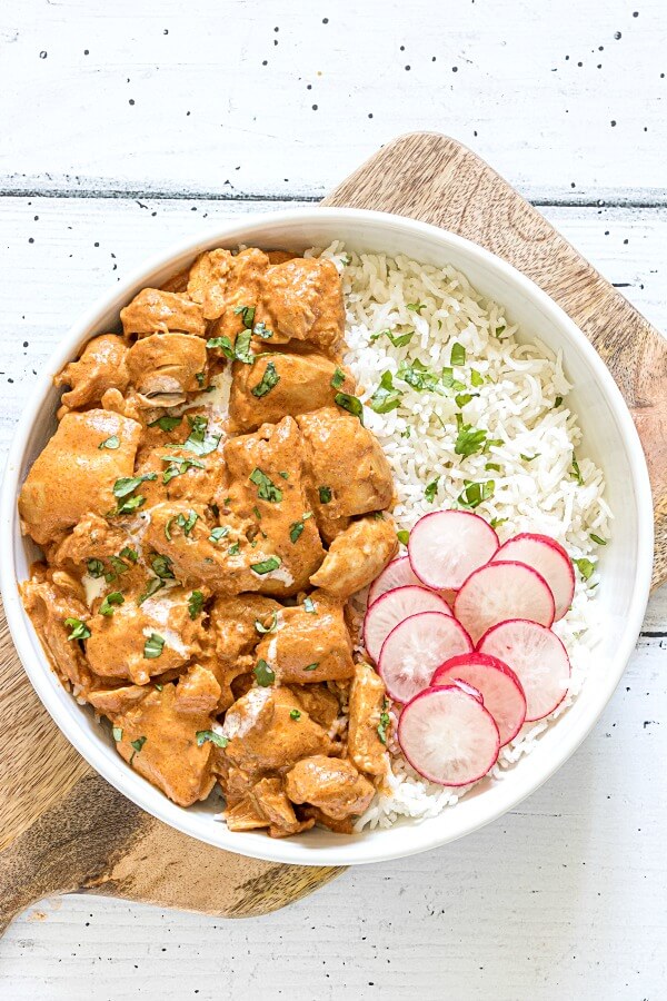 Instant Pot Butter Chicken in white bowl with rice and sliced radishes