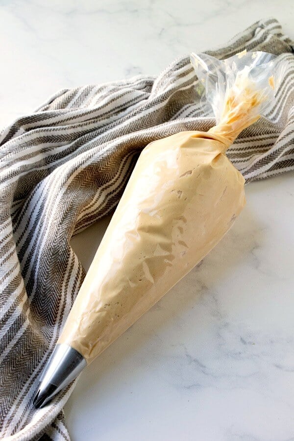 peanut butter frosting in frosting bag with towel beside