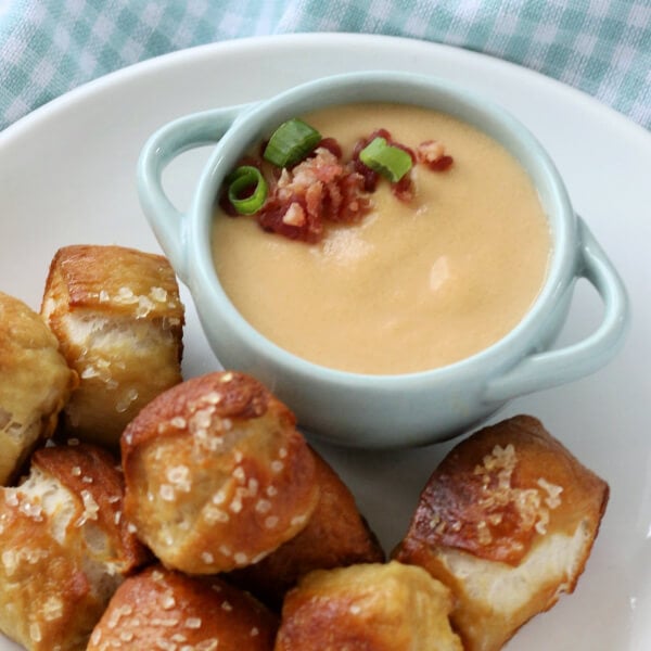 beer cheese dip in small bowl with pretzel bites on side