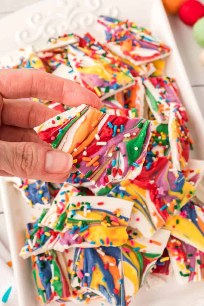 hand holding a piece of rainbow candy bark